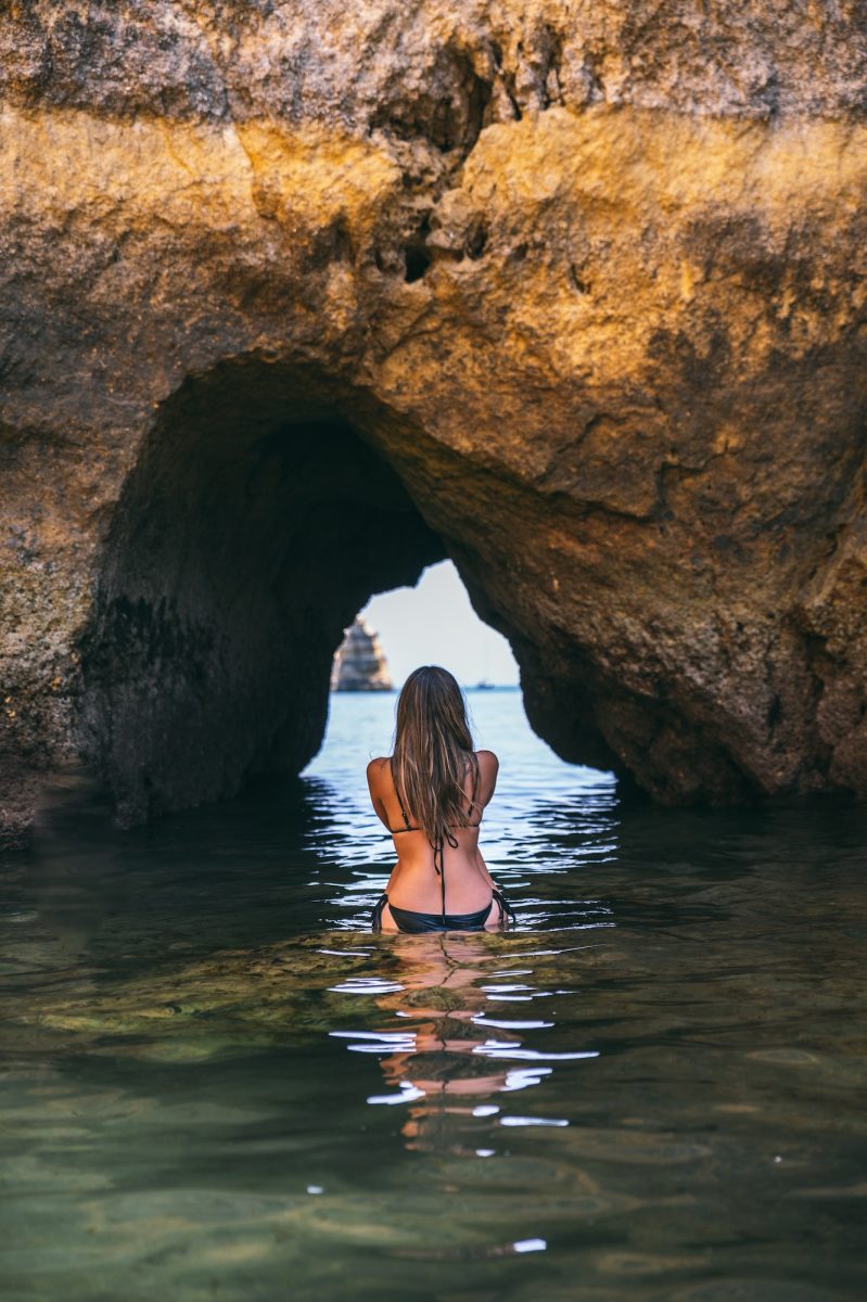 Woman in sea near cave